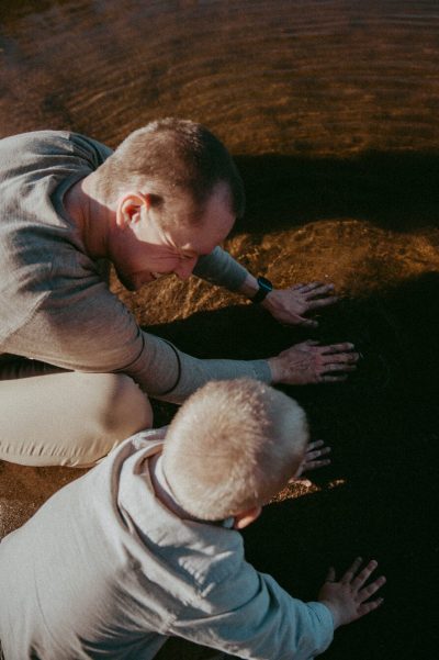 Eetu Oinas leikkii lapsen kanssa kyykyssä maata koskettaen ja hymyillen